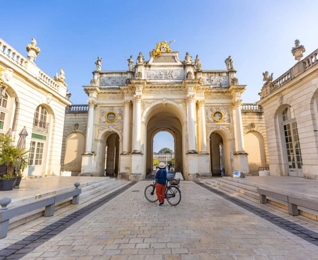 Cycliste passant sous l'arc Héré, place Stanislas à Nancy