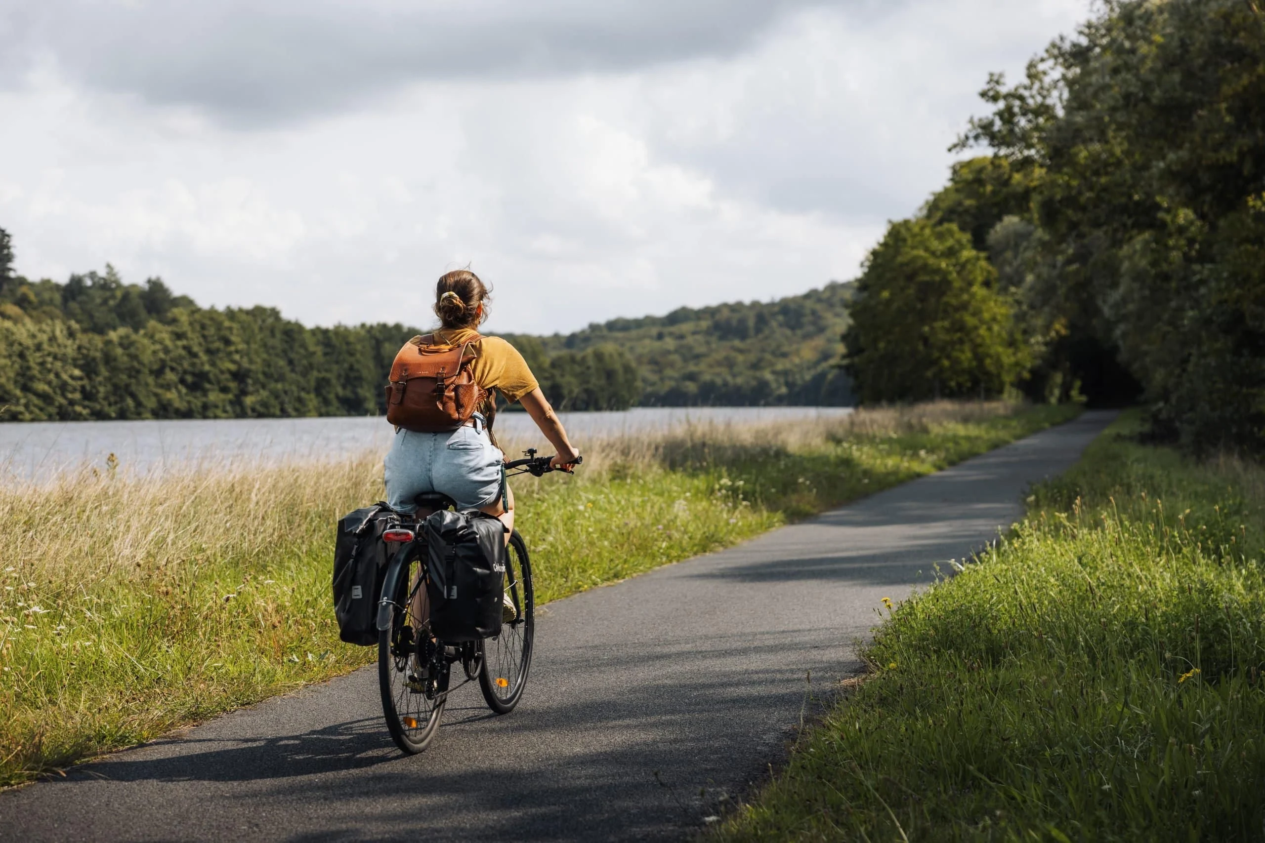 Cycliste avec sacoches sur une voie verte au bord de l'eau, Boucle de la Moselle