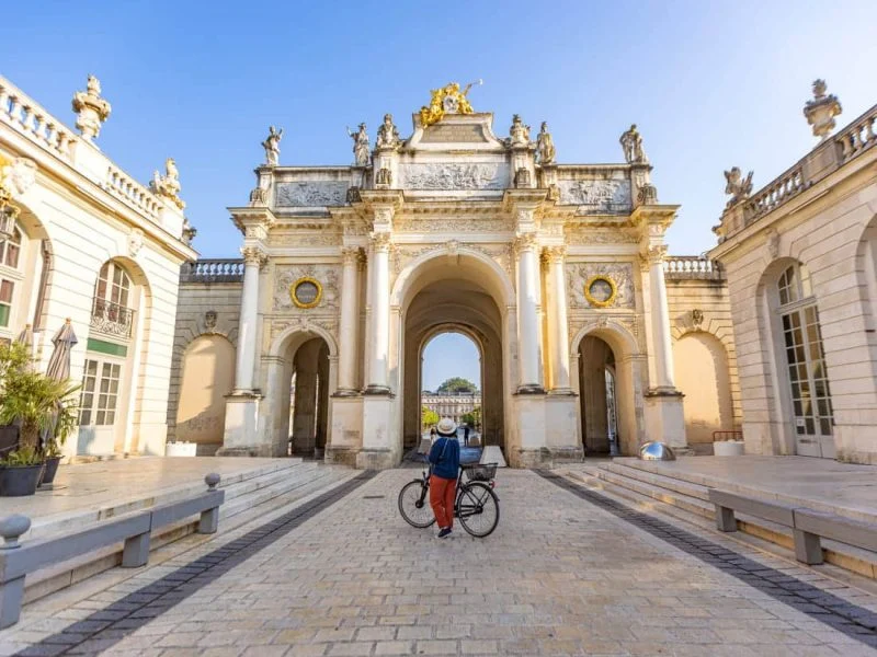 Cycliste passant sous l'arc Héré, place Stanislas à Nancy