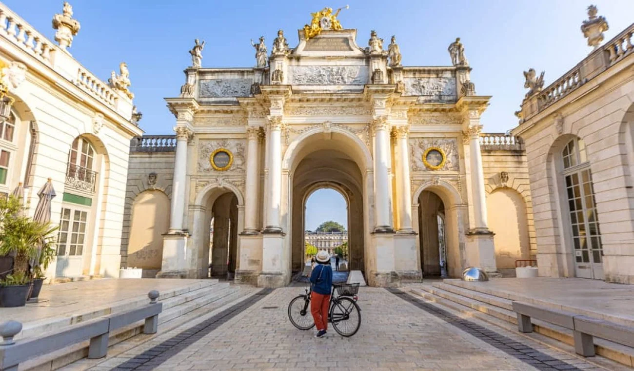 Cycliste passant sous l'arc Héré, place Stanislas à Nancy
